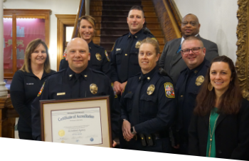 The chief of police holding an awarded certificate with the deputy chief and other officers standing beside and behind him.