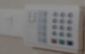 A faded image of a home alarm system with an open panel door.
