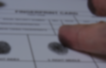A faded close-up image of someone just finishing getting their fingerprint taken on an official form.